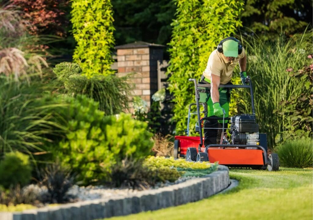 man performing lawn service man working on aerating a backyard